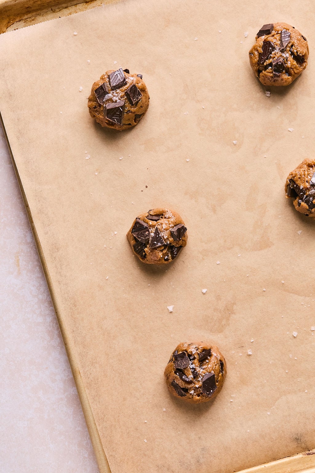 coconut flour cookie dough balls on a parchment lined baking sheet.