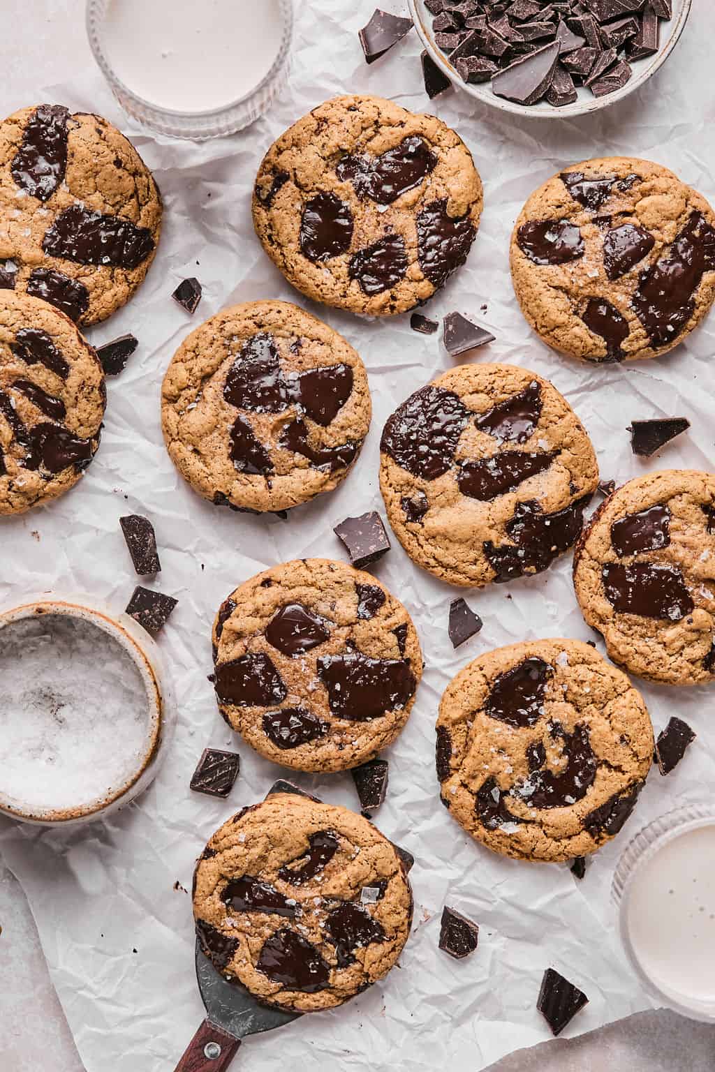 a batch of coconut flour cookies on parchment paper with a glass of milk.