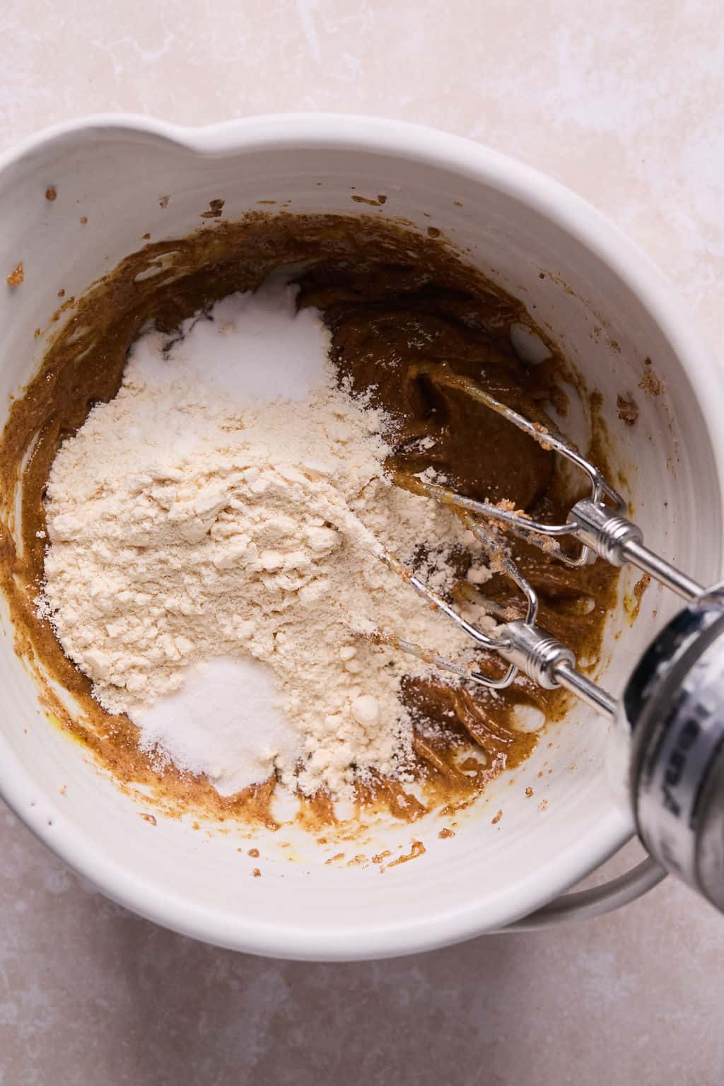 a bowl of coconut flour in cookie dough with an electric mixer. 