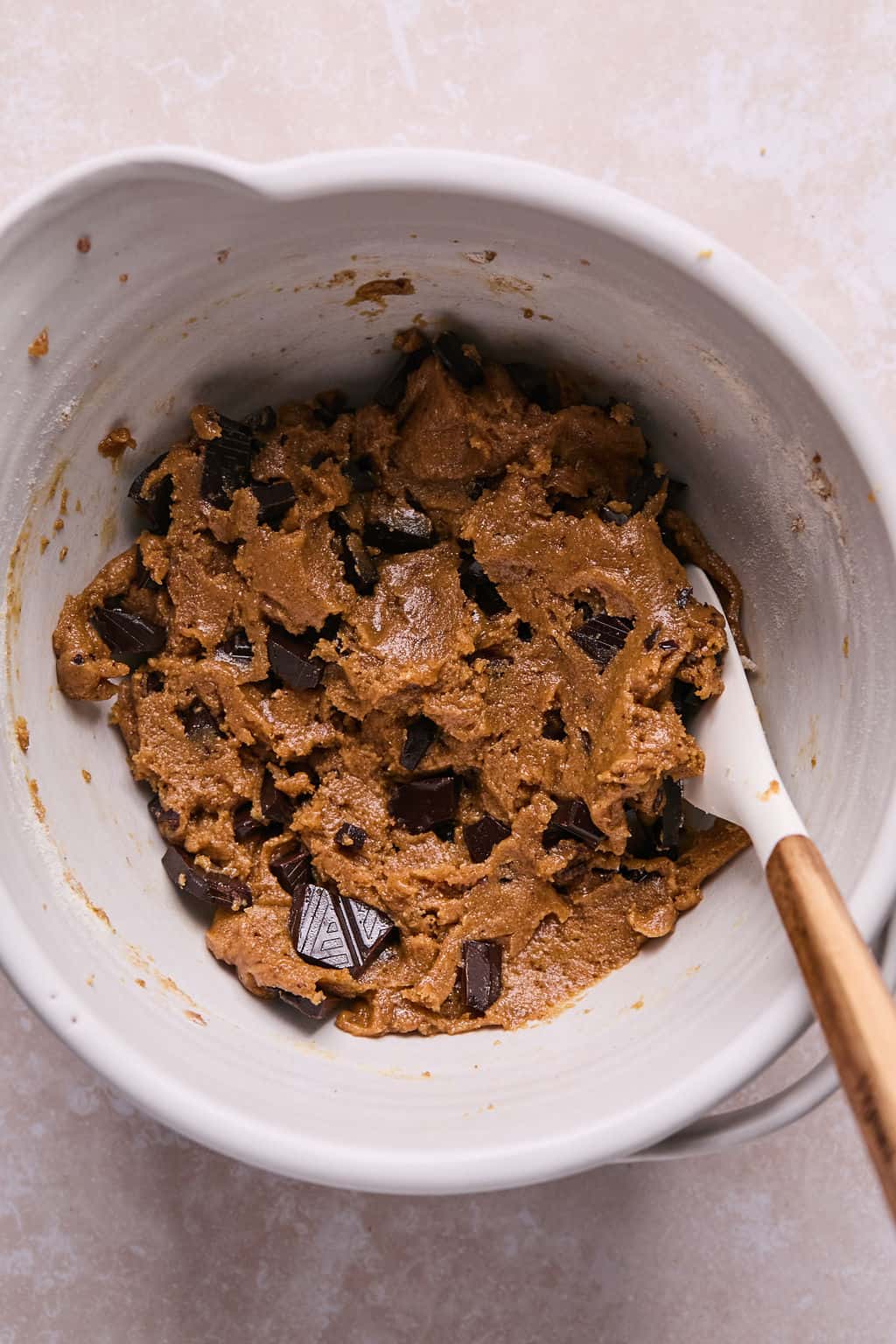 coconut flour cookie dough with chocolate chips in a mixing bowl with a rubber spatula.