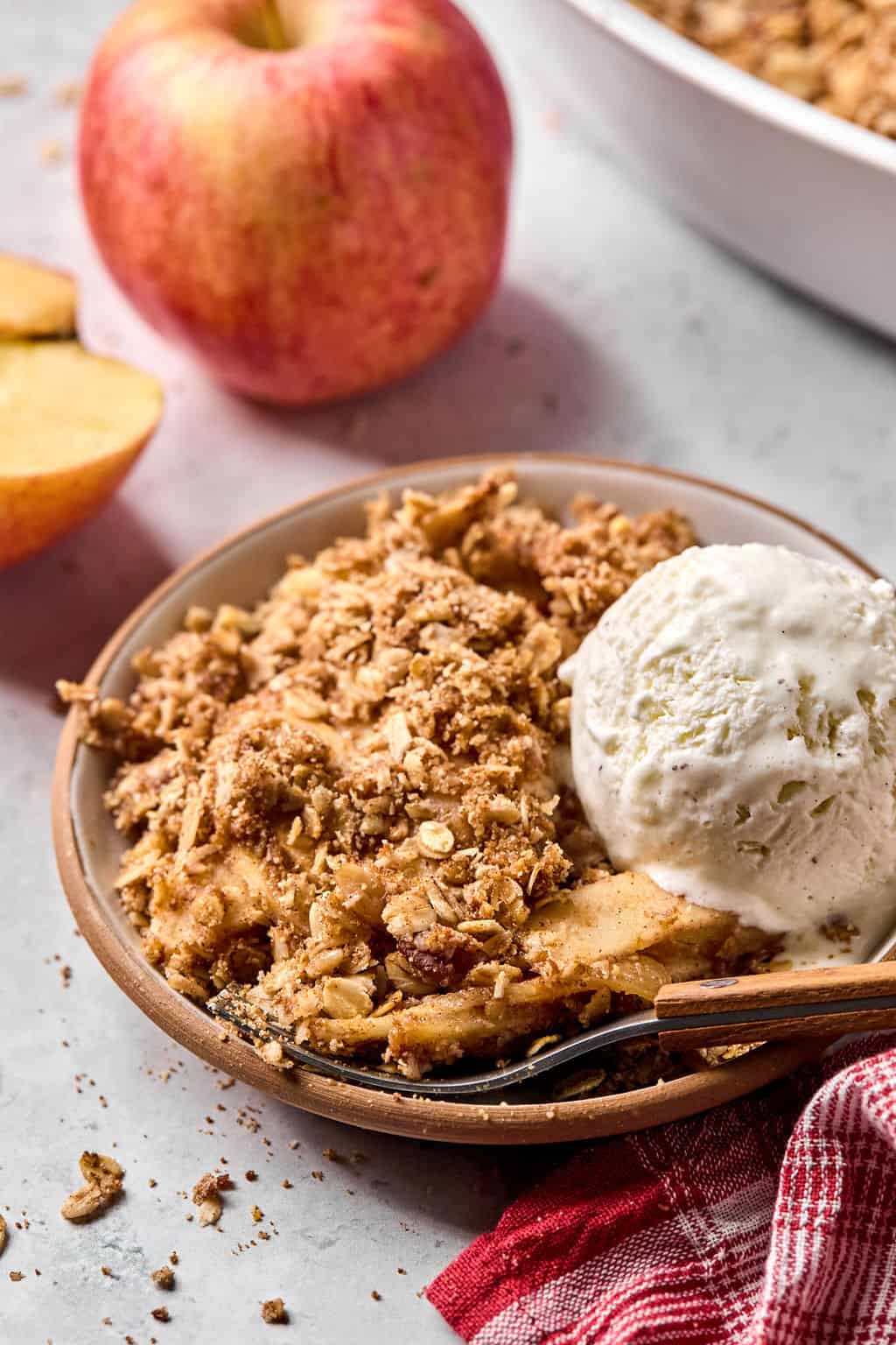 a plate of healthy apple crisp with a scoop of vanilla ice cream on top.