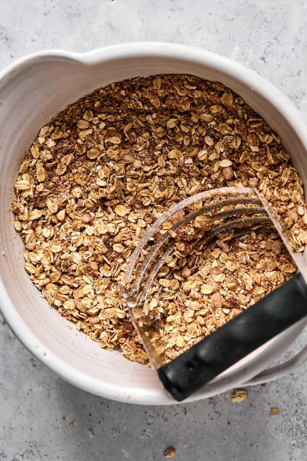 healthy apple crisp oat topping in a a bowl with a pastry blender.