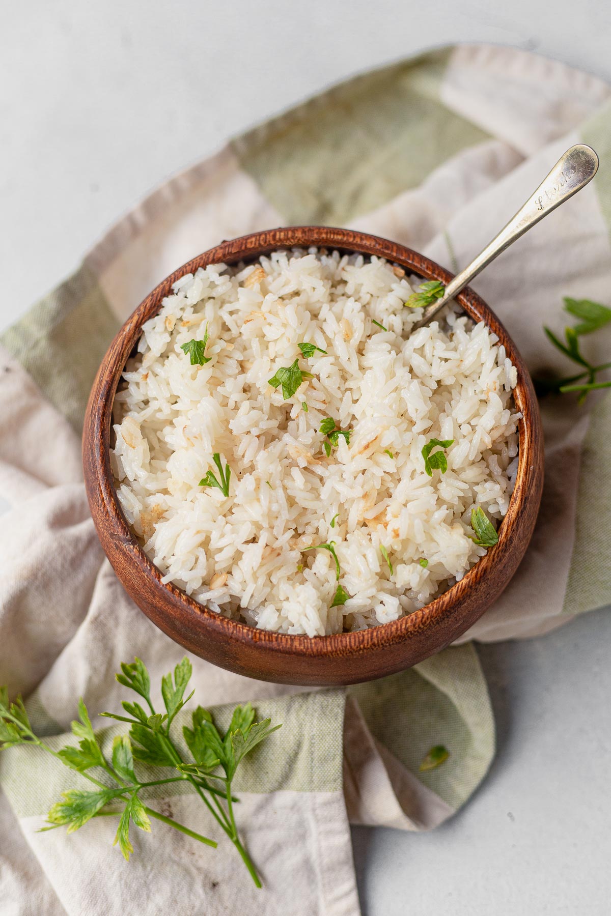 coconut rice in a wooden bowl on a napkin topped with cilantro