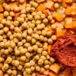 red curry paste, sweet potatoes, and chickpeas simmering in a pot.
