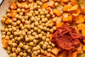 red curry paste, sweet potatoes, and chickpeas simmering in a pot.