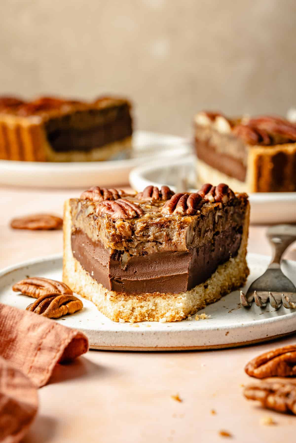 a piece of chocolate paleo pecan pie on a plate with a bite missing.