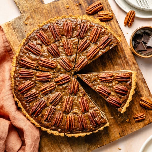 chocolate paleo pecan pie on a cutting board with a piece missing.