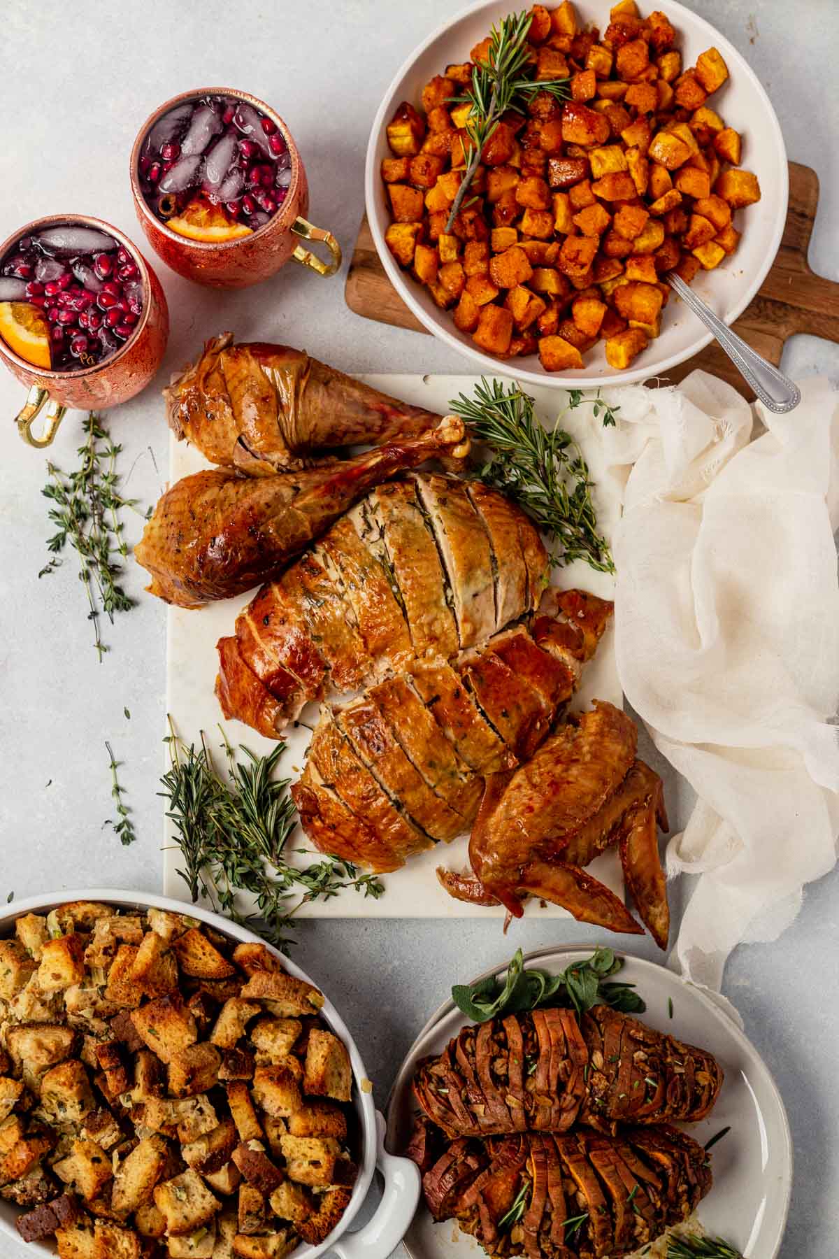 roasted and carved cheesecloth turkey on a table with classic thanksgiving sides