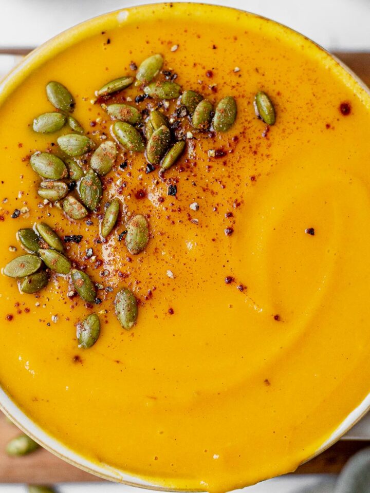 creamy panera autumn squash soup recipe swirled in a bowl and topped with pumpkin seeds