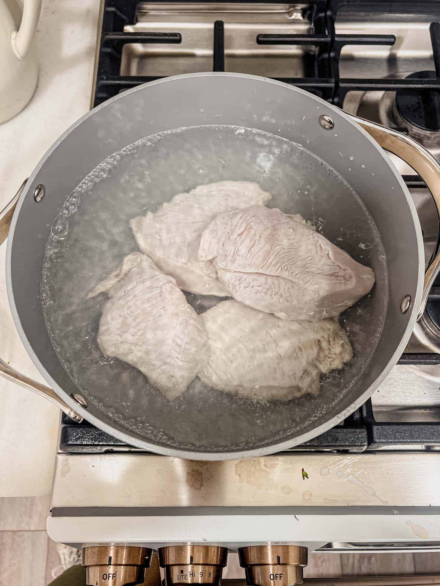 poaching chicken breasts in a pot on the stove