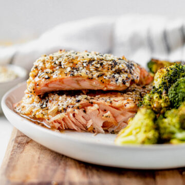 flaky salmon fillet on a white plate with everything bagel seasoning and a side of roasted broccoli