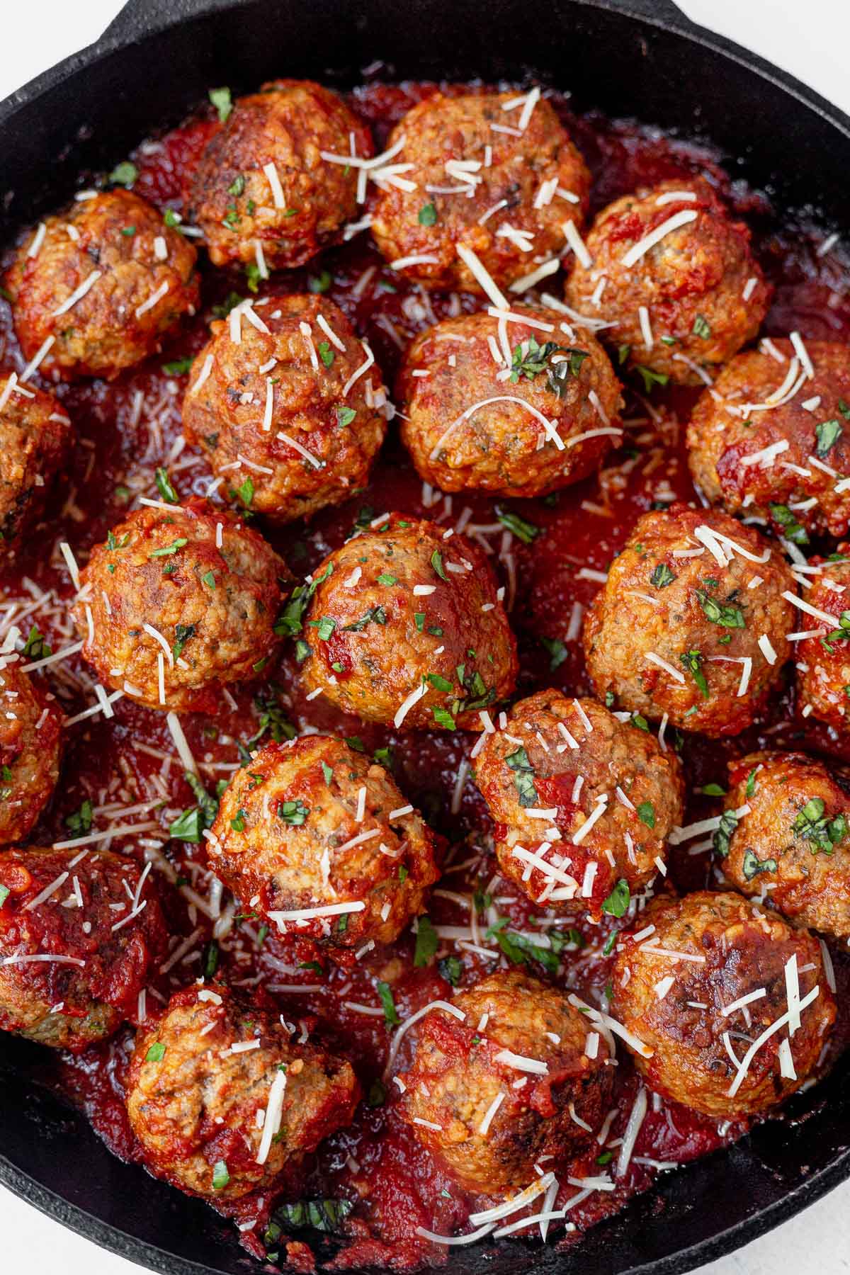 gluten free meatballs in a cast iron skillet topped with parmesan cheese