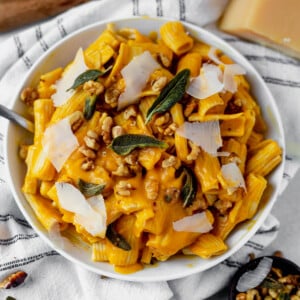 a bowl of butternut squash pasta topped with sage and walnut