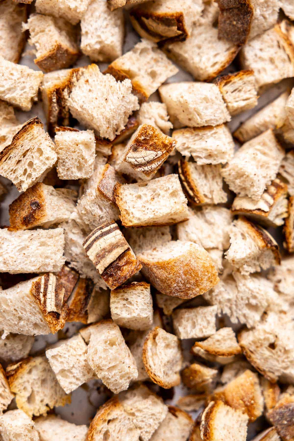 cubed sourdough bread drying out on a sheet pan.