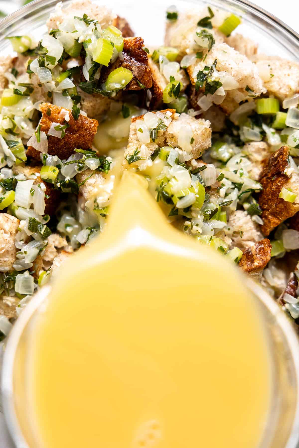 pouring broth and egg mixture over sourdough stuffing.