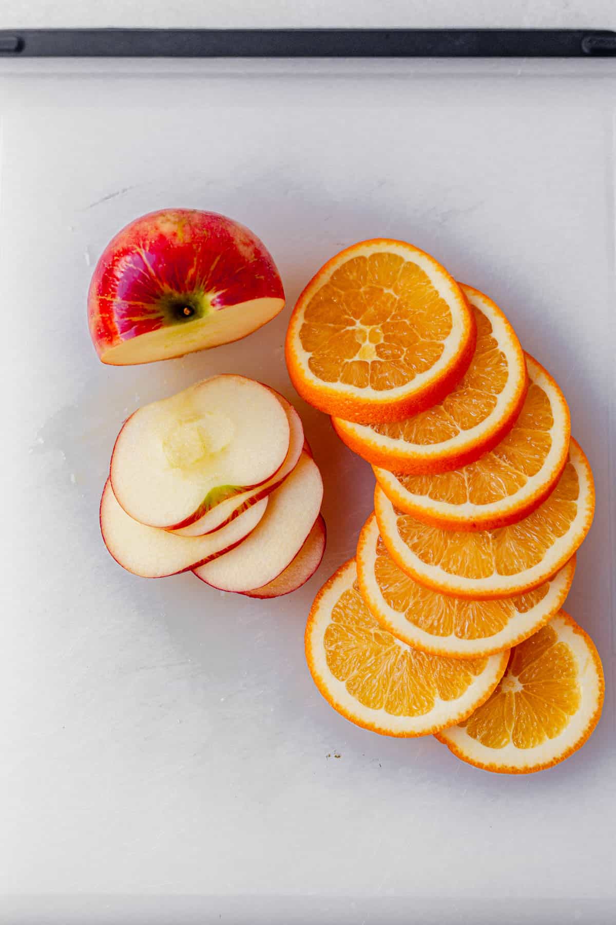 sliced apples and oranges on a cutting board.