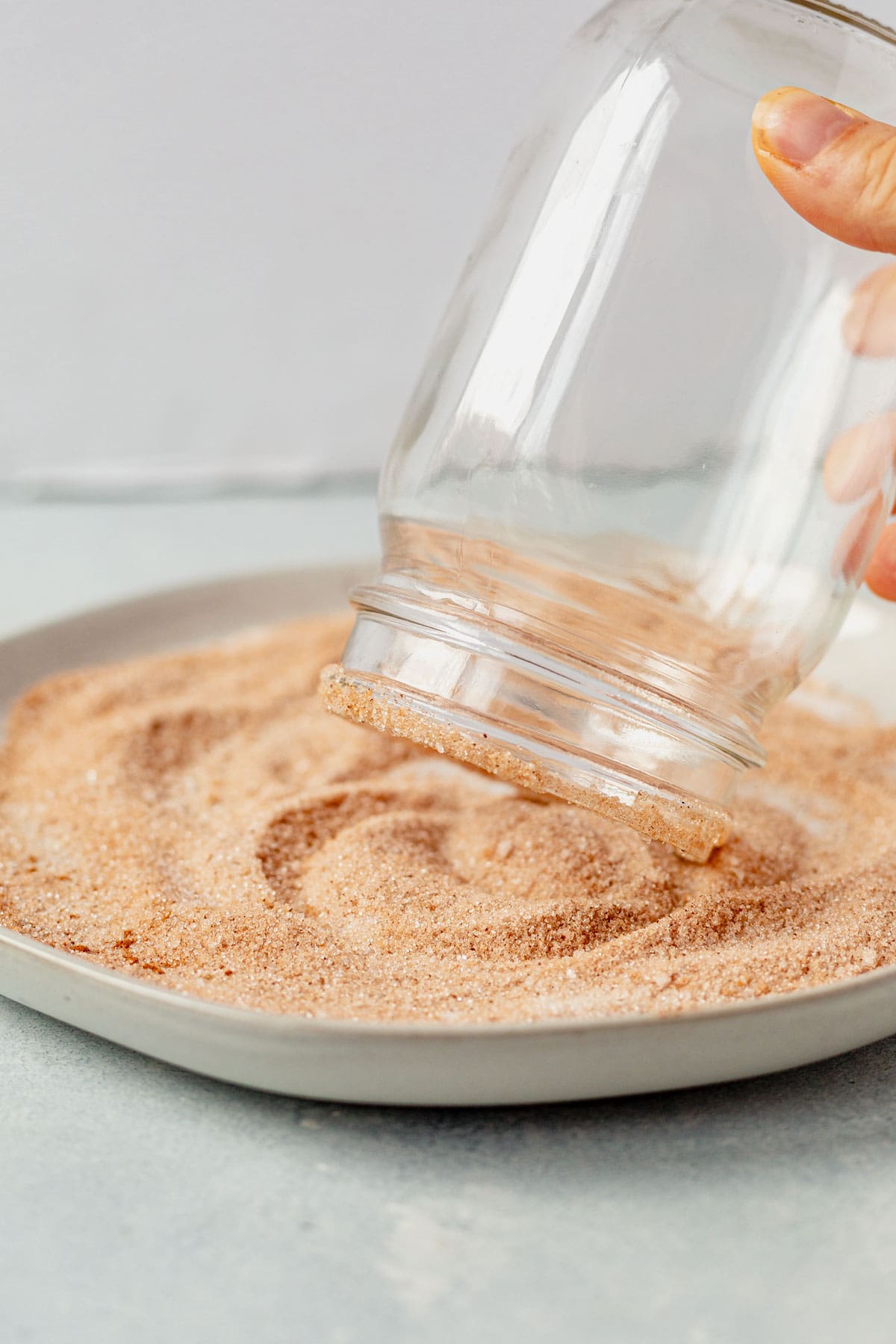 dipping the rim of a mason jar into cinnamon sugar.