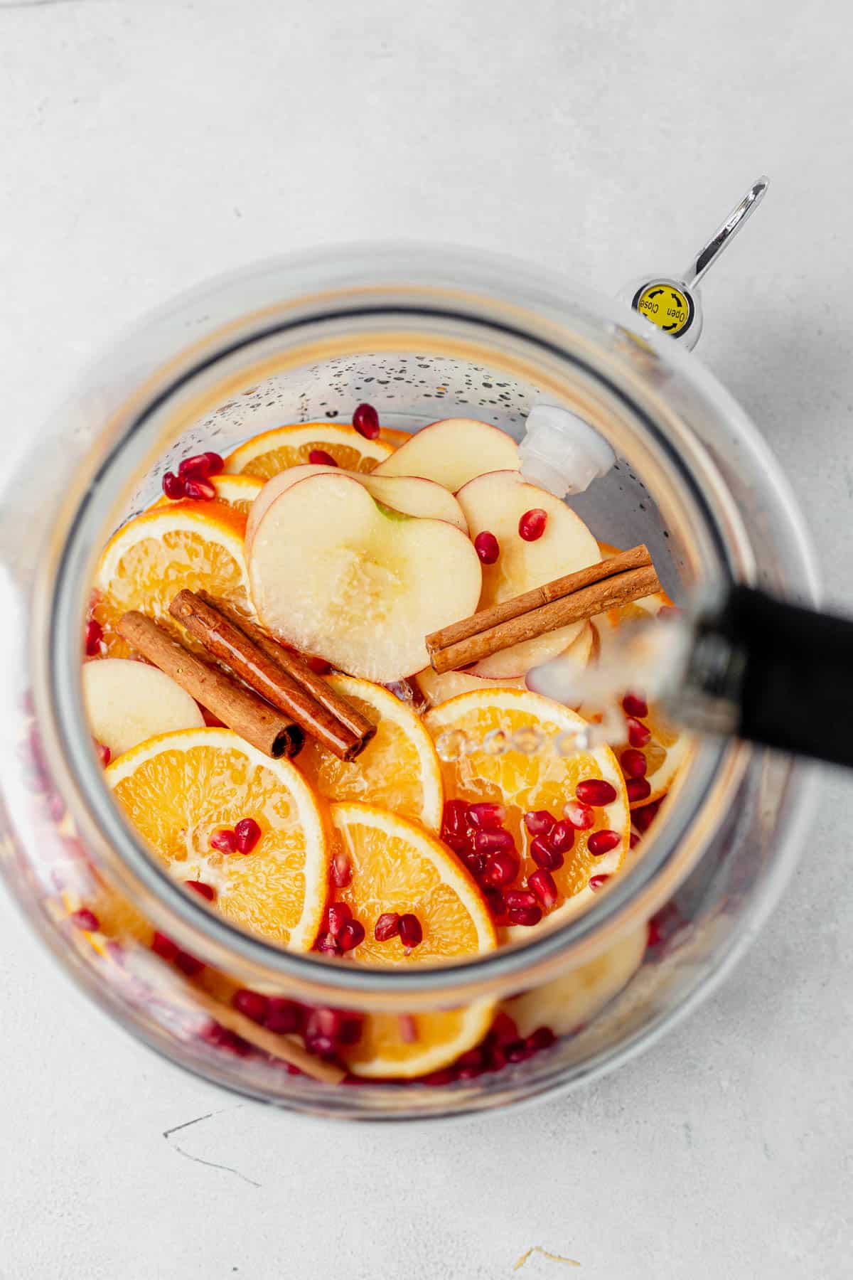 pouring white wine in a pitcher to make apple cider sangria.