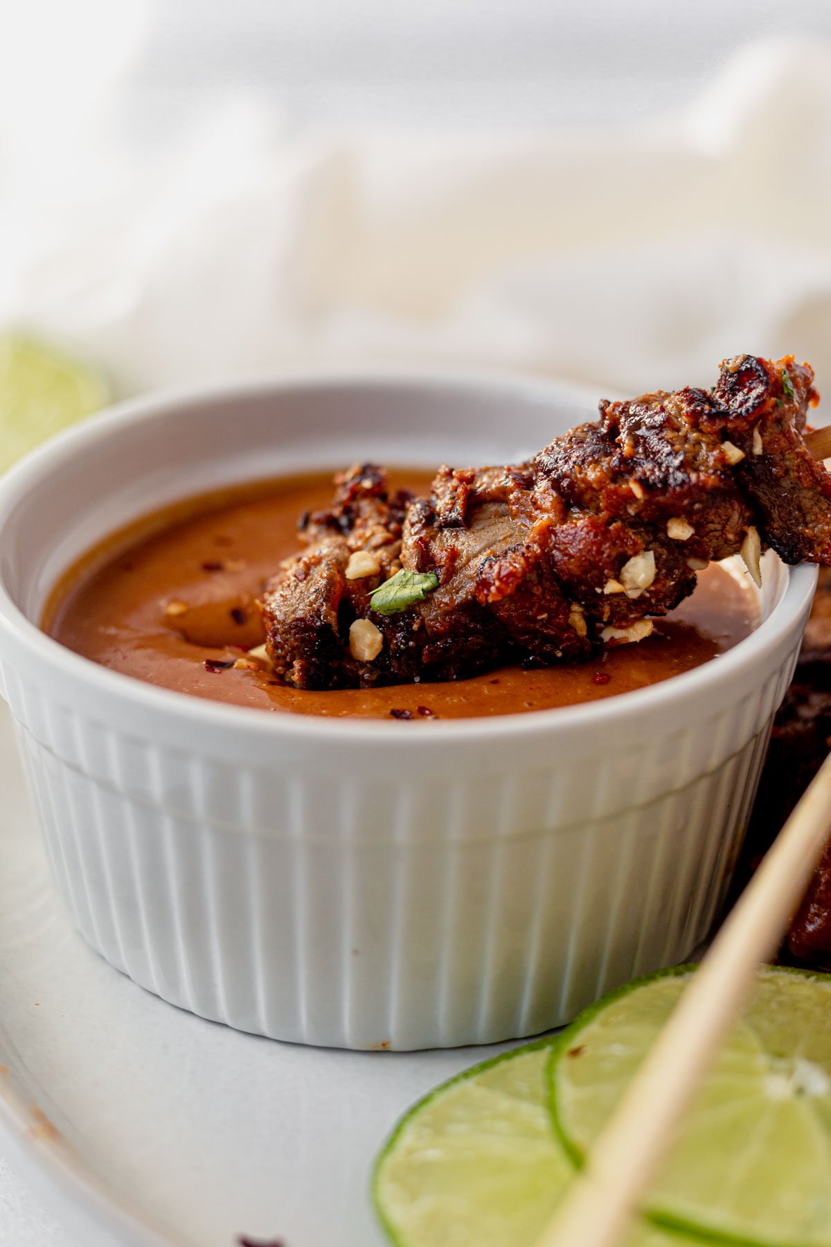beef satay skewer dipping into a bowl of thai peanut sauce