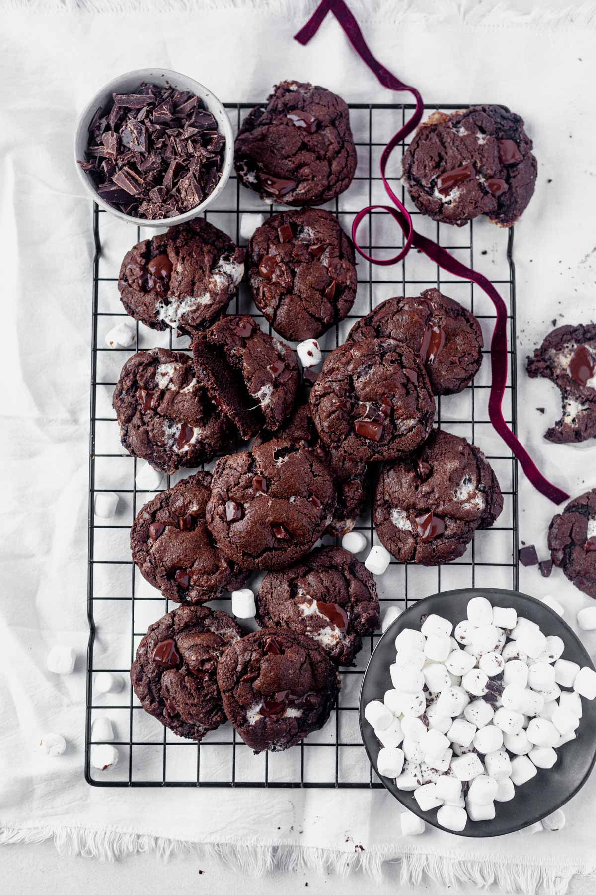 chocolate chunk marshmallow cookies on a cooling rack with a bowl of mini marshmallows