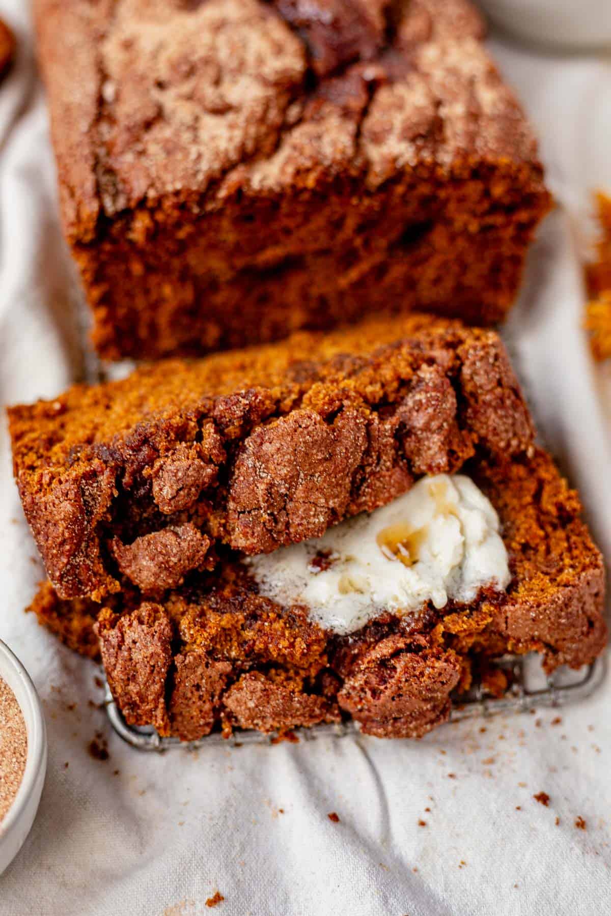 two slices of cinnamon pumpkin bread lying next to the loaf.