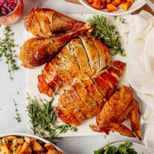 cheesecloth turkey with butter and herbs on a serving tray with fresh rosemary