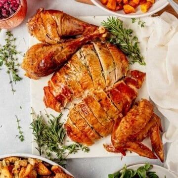 cheesecloth turkey with butter and herbs on a serving tray with fresh rosemary