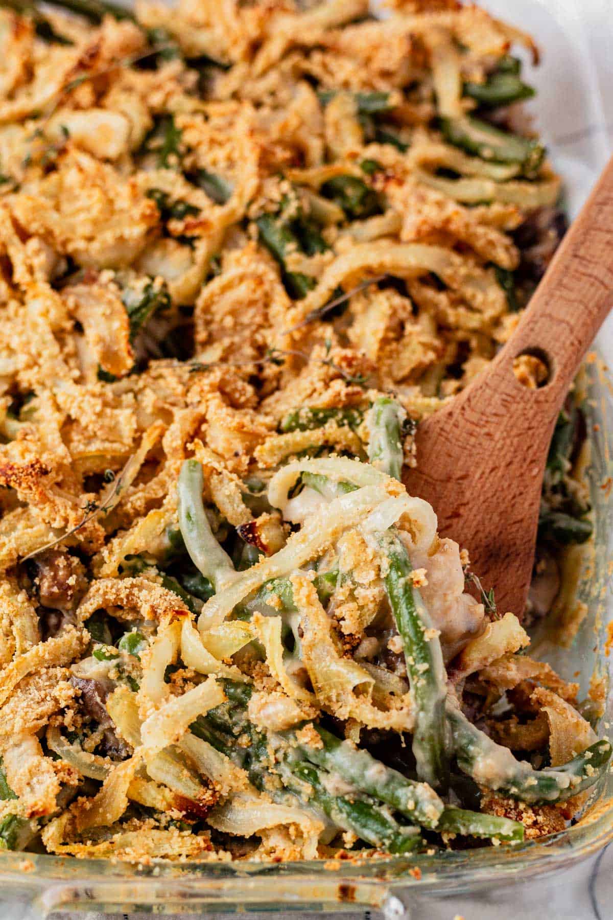 scooping dairy and gluten free green bean casserole out of a serving dish.