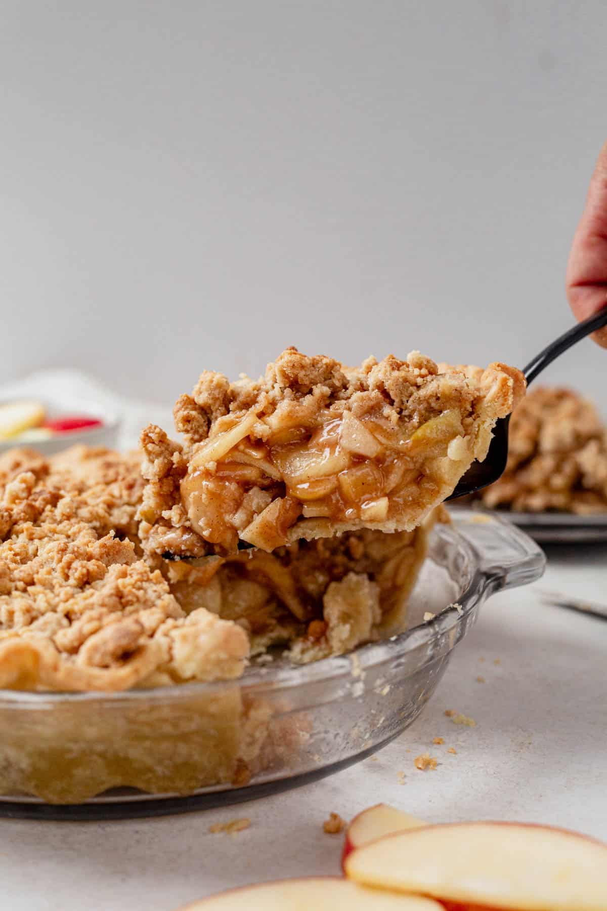 lifting a piece of gluten free dutch apple pie from the pie pan.