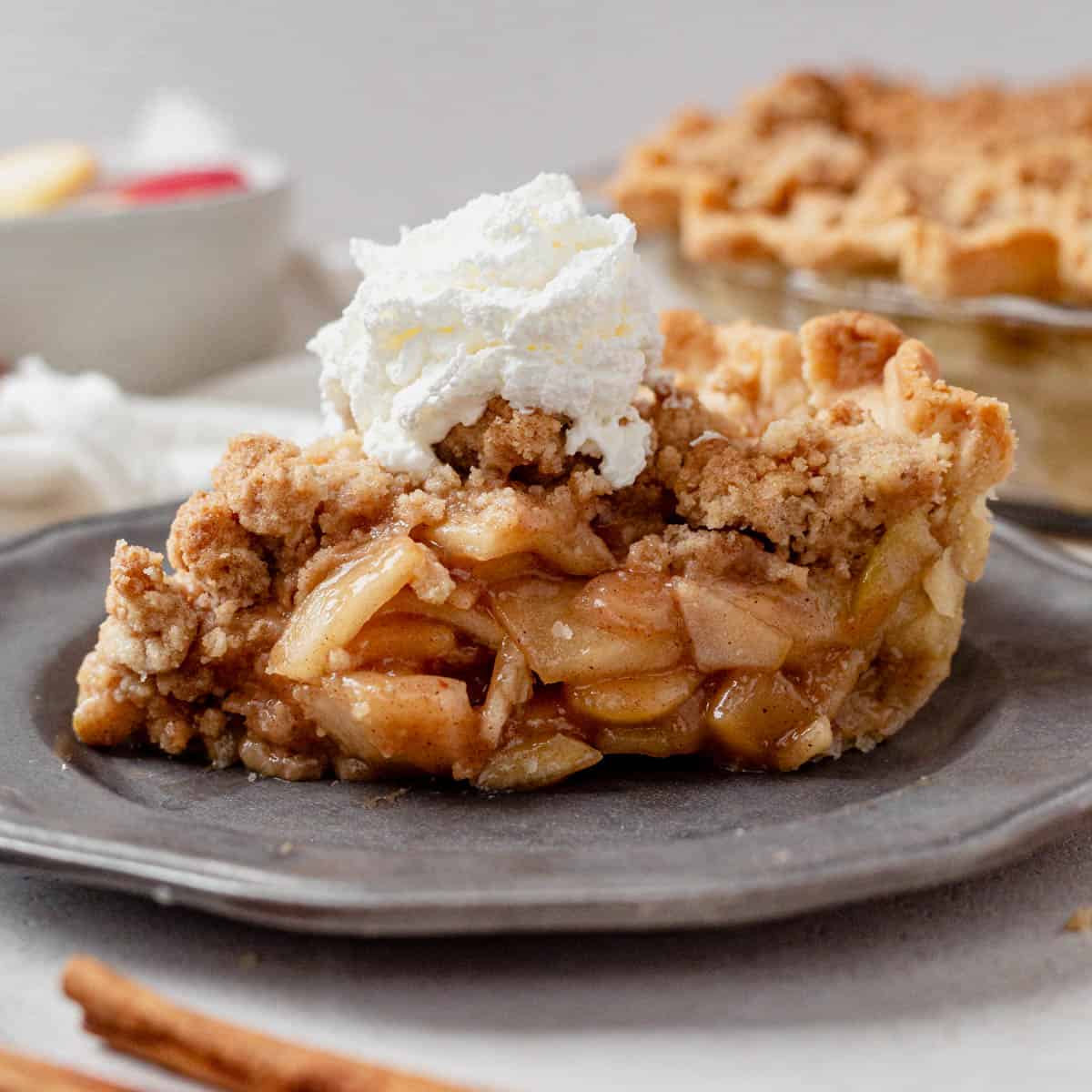 a slice of gluten free dtuch apple pie on a plate with whipped cream.