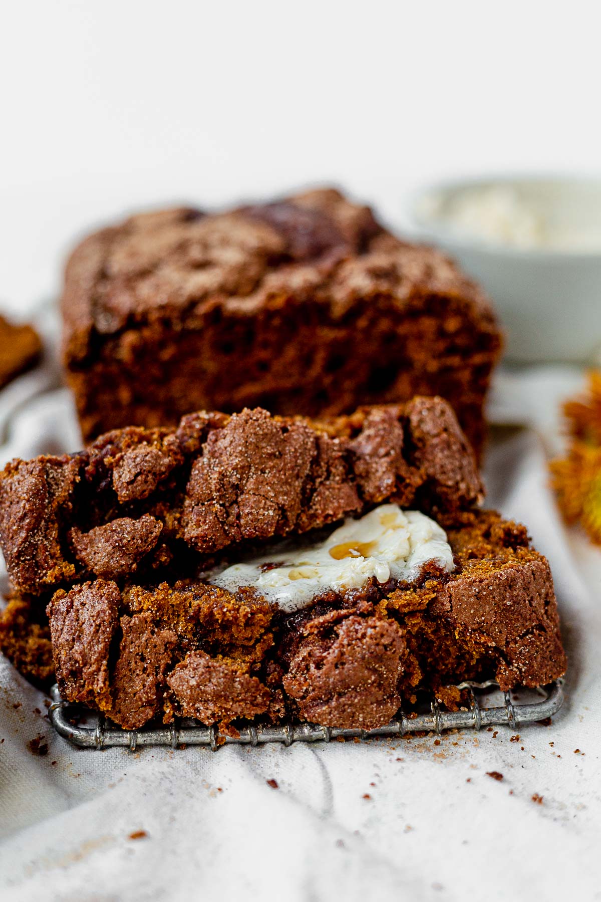 two slices of gluten free pumpkin bread on a cooling rack with softened butter