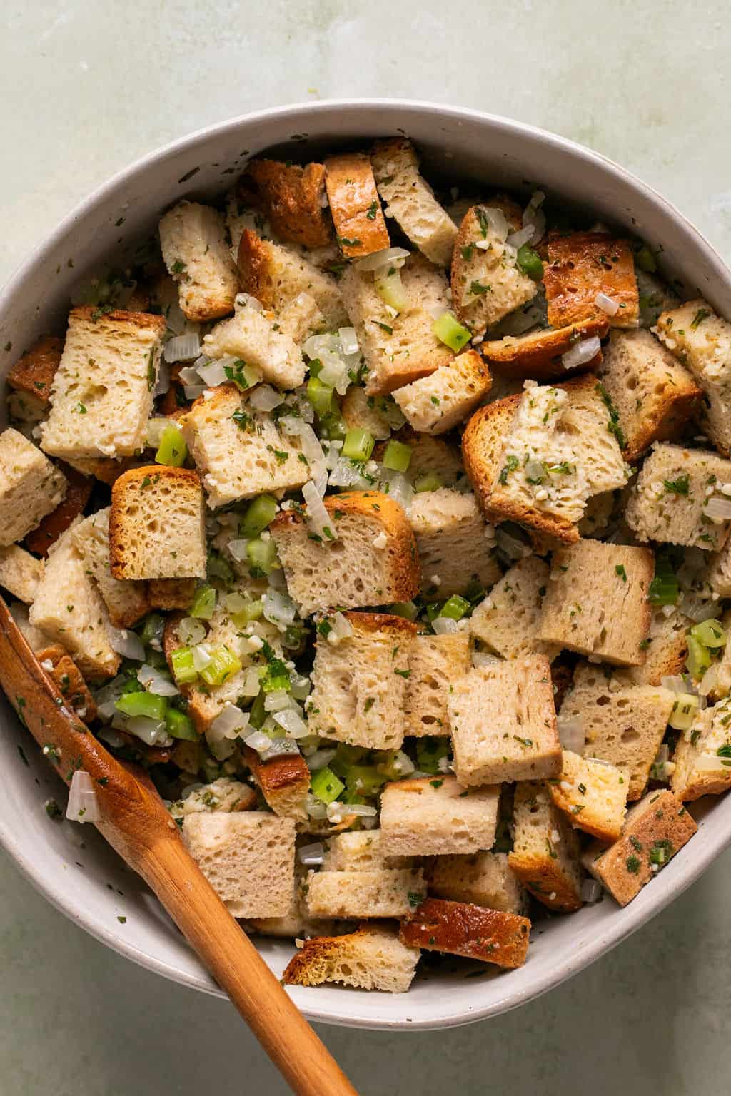 crusty bread cubes in a mixing bowl with sauteed celery, onion, and herbs.