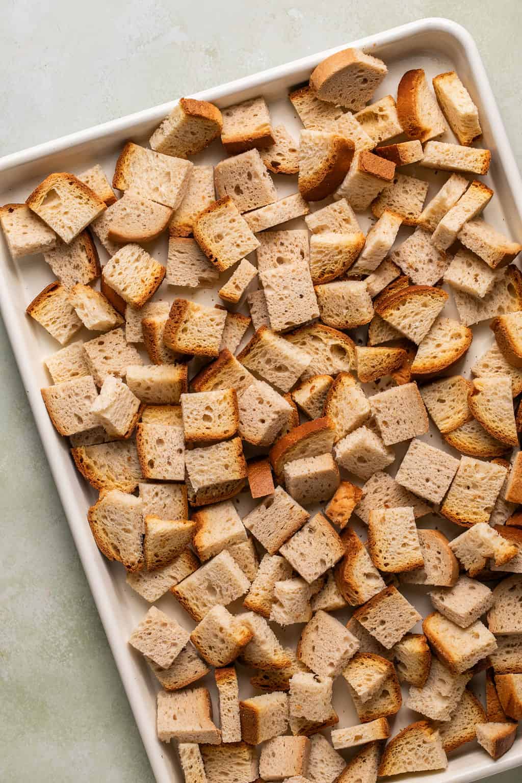 gluten-free bread cubes drying out on a sheet pan.