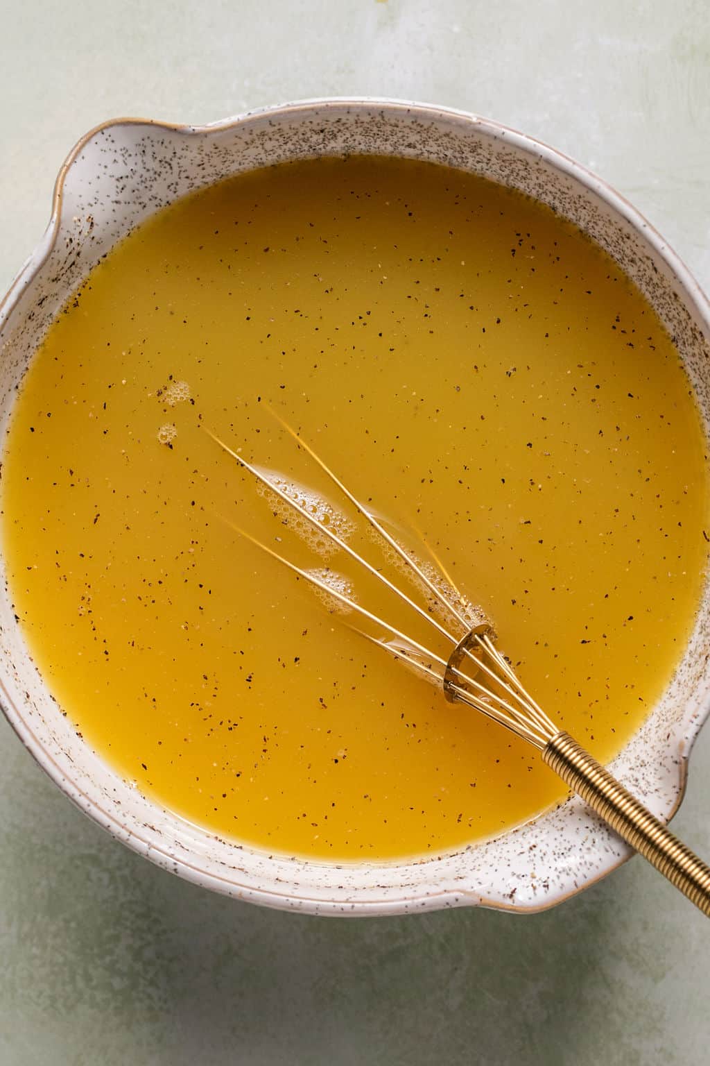 broth and eggs whisked together in a mixing bowl.