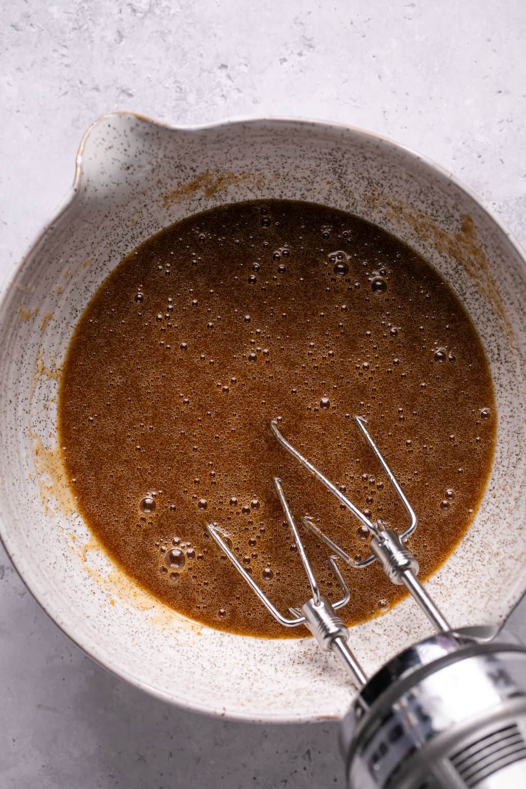 maple pecan cookie wet ingredients in a mixing bowl with an electric mixer.