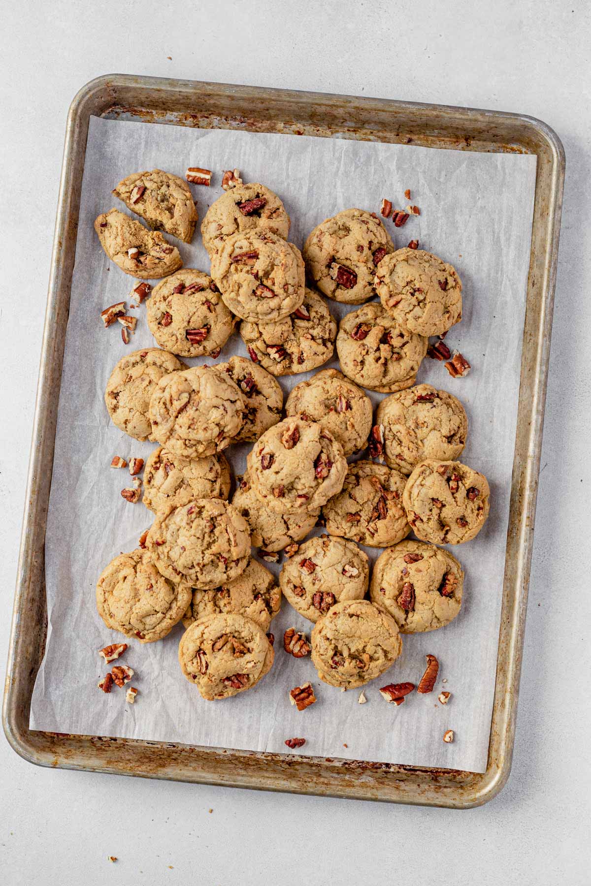 a pile of maple pecan cookies piled onto a cookie sheet with parchment paper