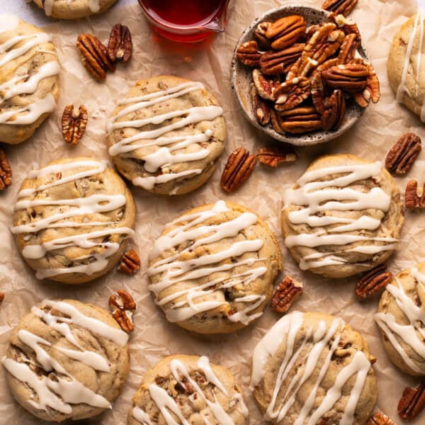 maple pecan cookies topped with maple icing on a piece of parchment paper.