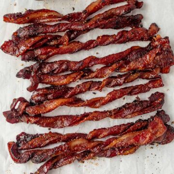twisted bacon topped with black pepper on a plate