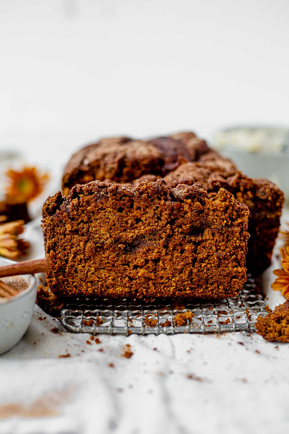 a slice of cinnamon swirl gluten free pumpkin bread standing up against the rest of the loaf