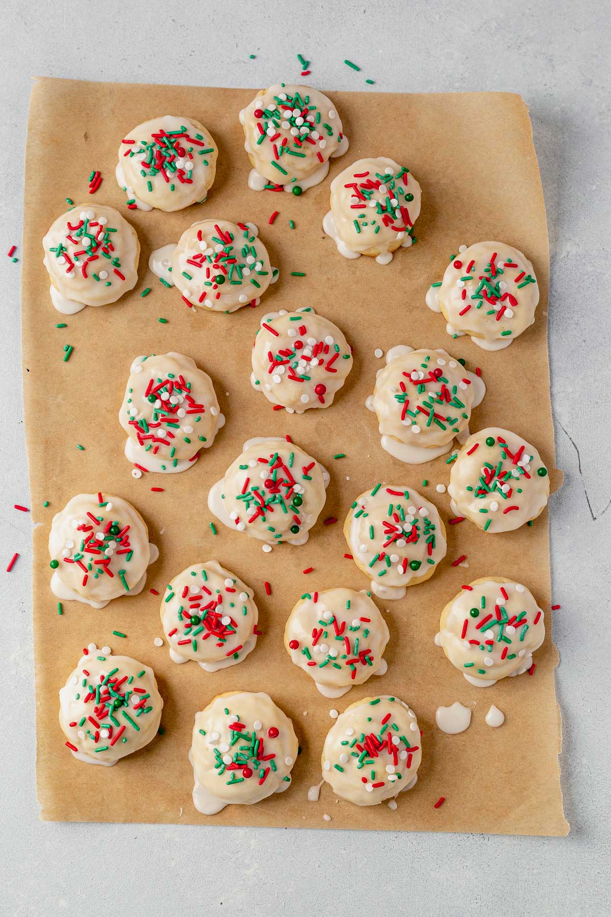 italian sprinkle cookies resting on parchment paper while the icing sets