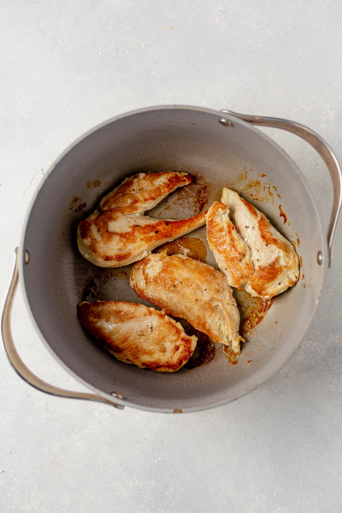 crispy golden chicken breasts searing in a dutch oven