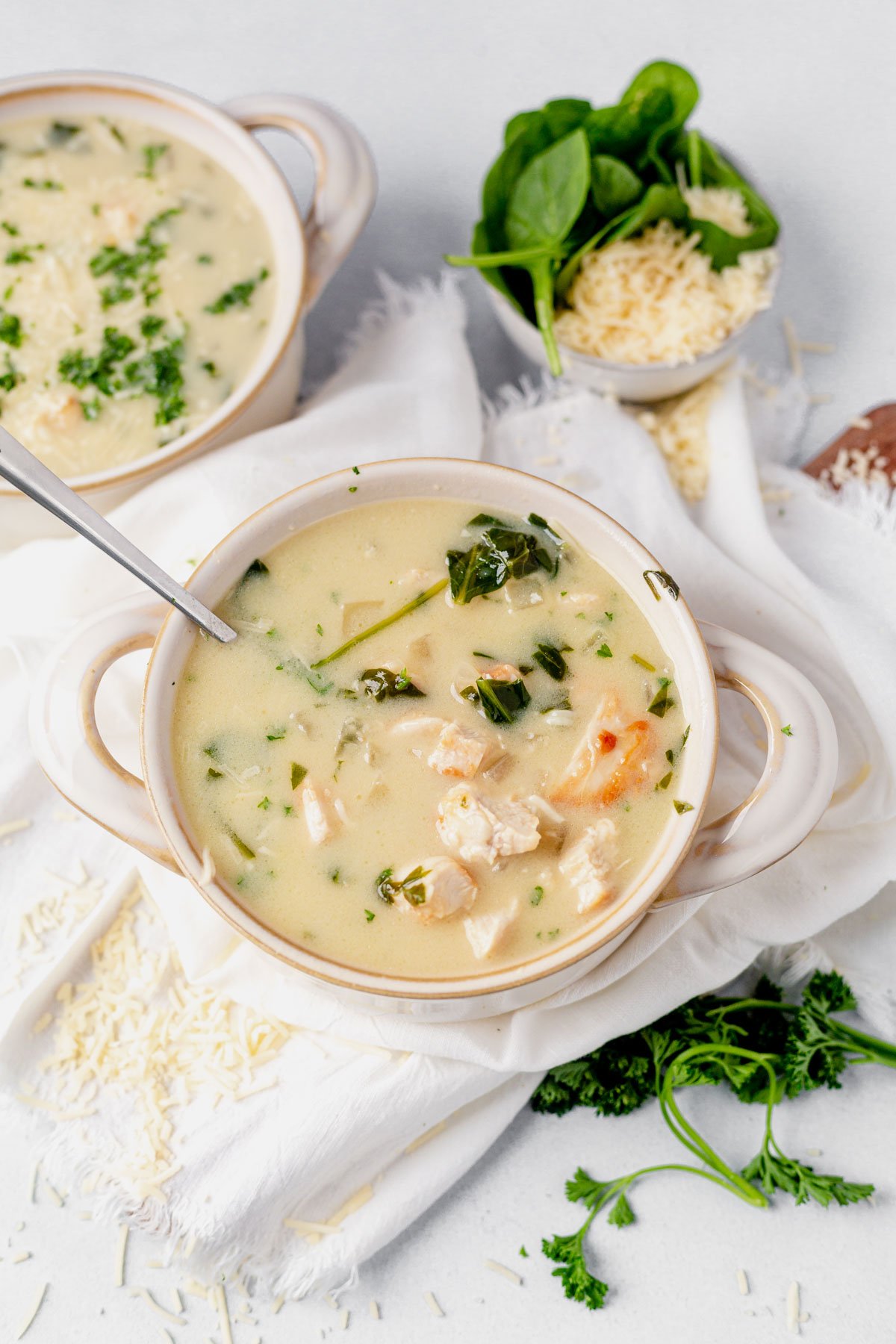 two bowls of chicken florentine soup topped with parmesan cheese