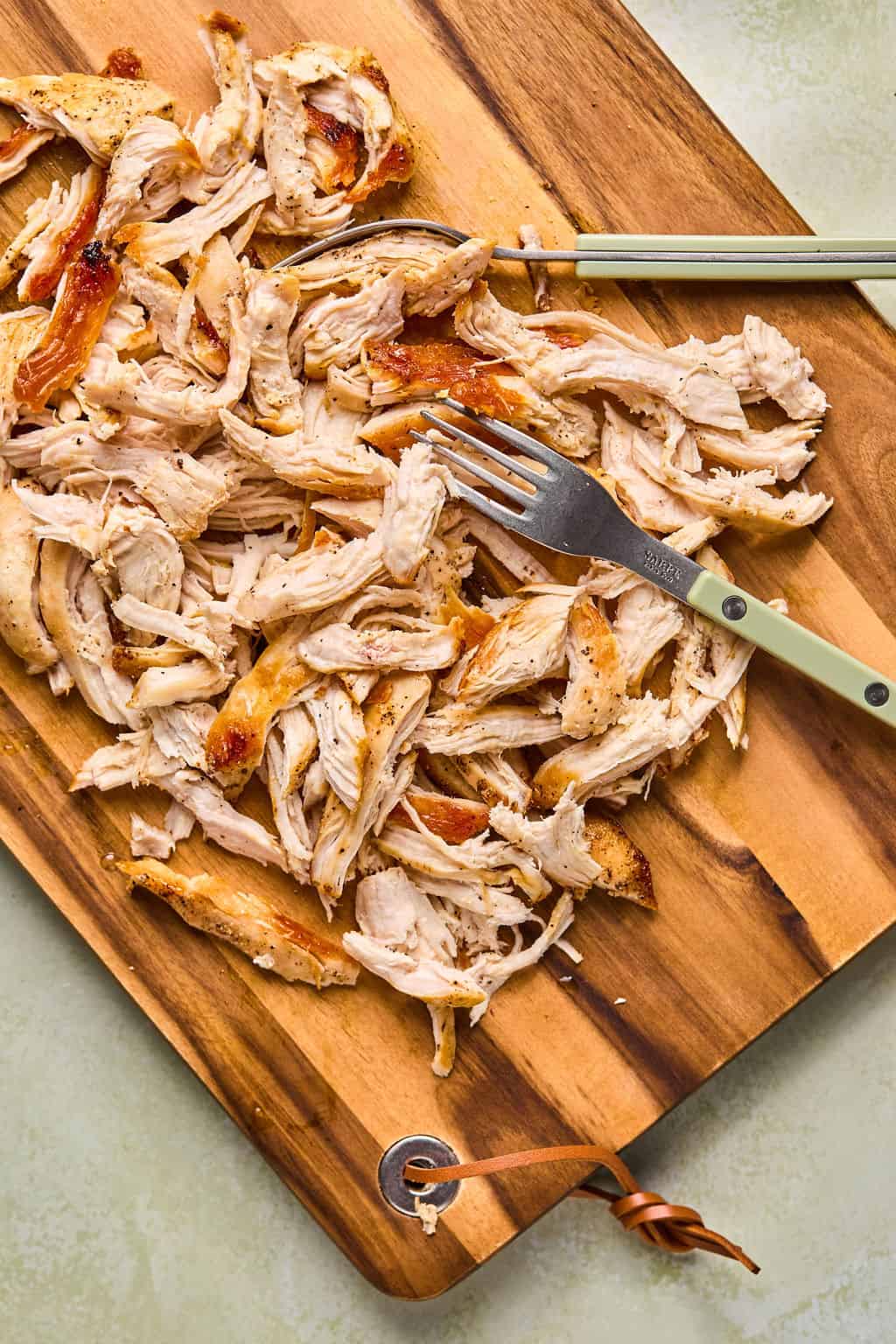 shredded chicken breasts on a cutting board with two forks.