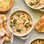 a bowl of chicken florentine soup with parmesan cheese and crusty bread.