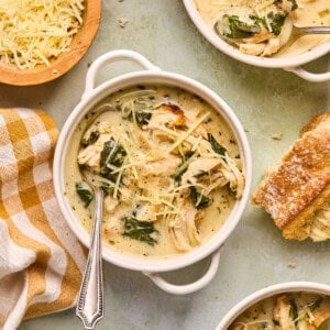 a bowl of chicken florentine soup with parmesan cheese and crusty bread.