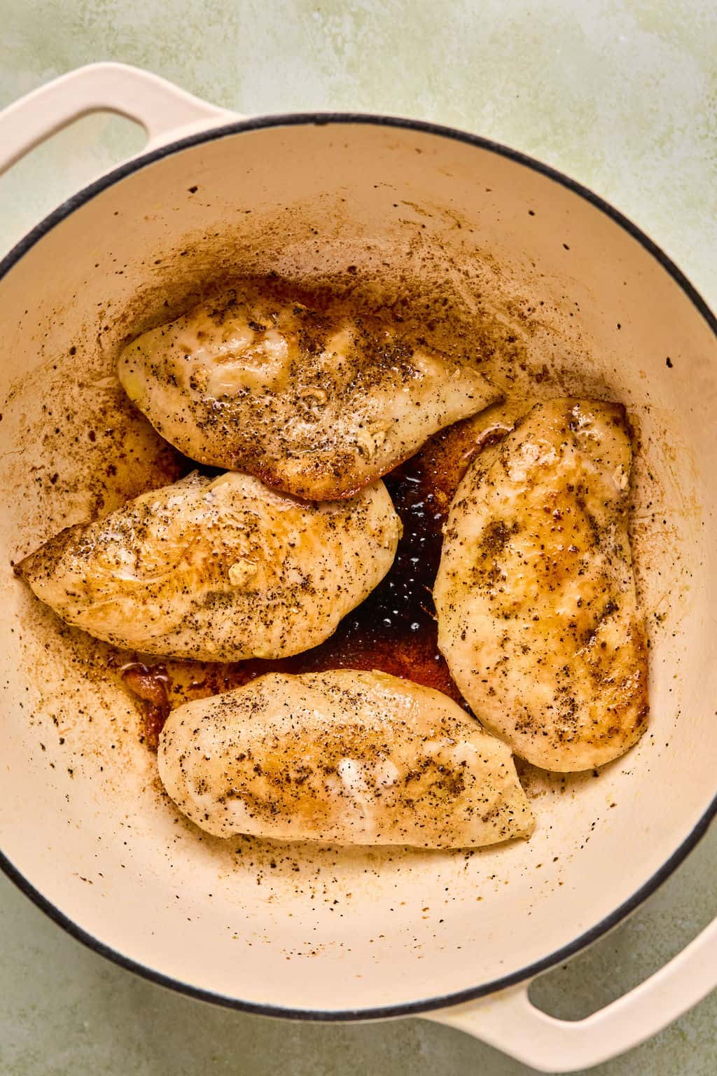 four seared chicken breasts in a dutch oven.