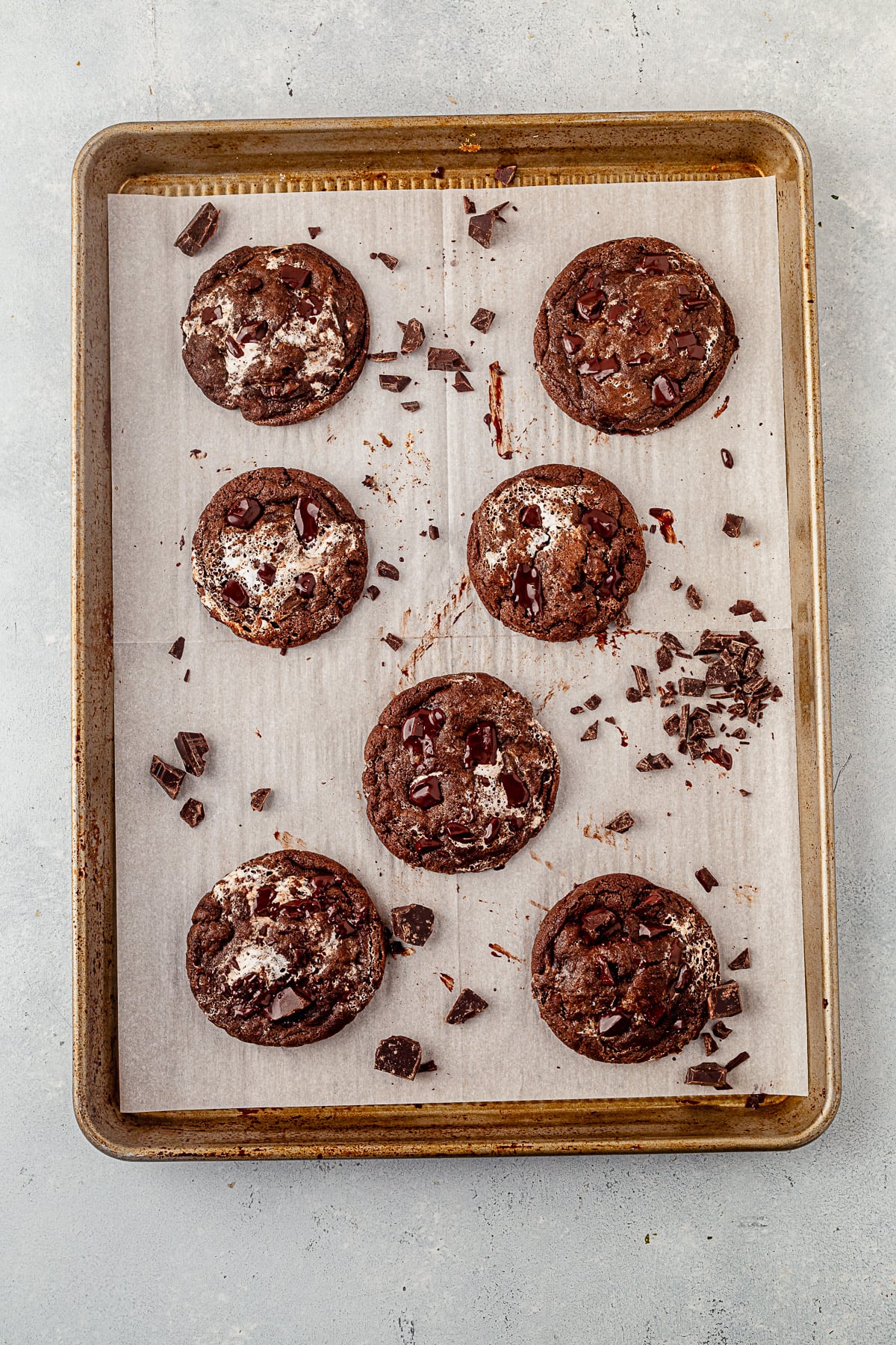 seven chocolate marshmallow cookies cooling on a parchment lined cookie sheet