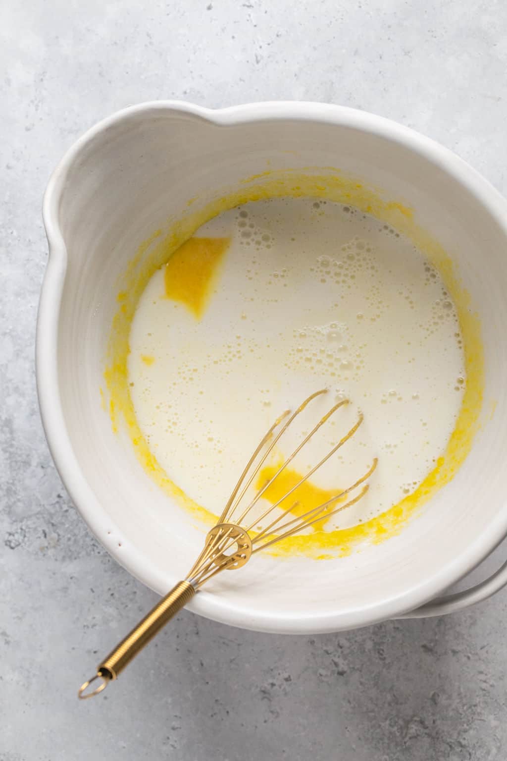 tempering hot milk into egg yolks and sugar in a mixing bowl.