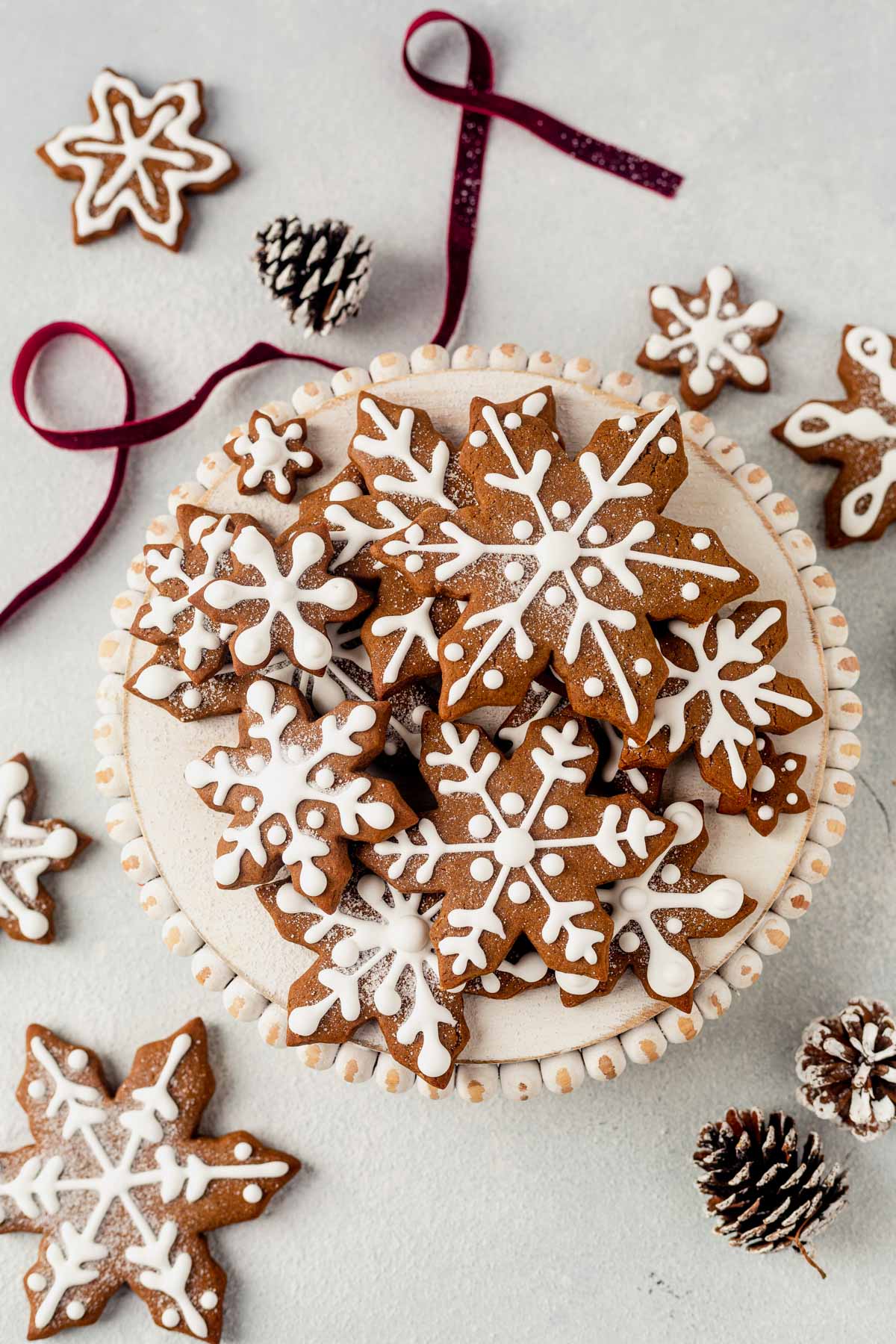 snowflake cookies decorated with royal icing stacked on a platter