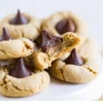 six gluten-free peanut butter blossoms stacked on a platter with a bite taken out of one
